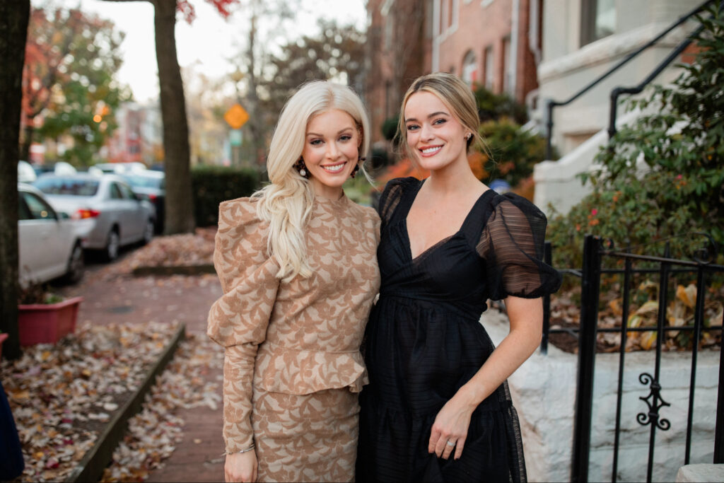 Alison Cheperdak smiling outdoors alongside a guest, both dressed elegantly for a modern etiquette event on a tree-lined city street.