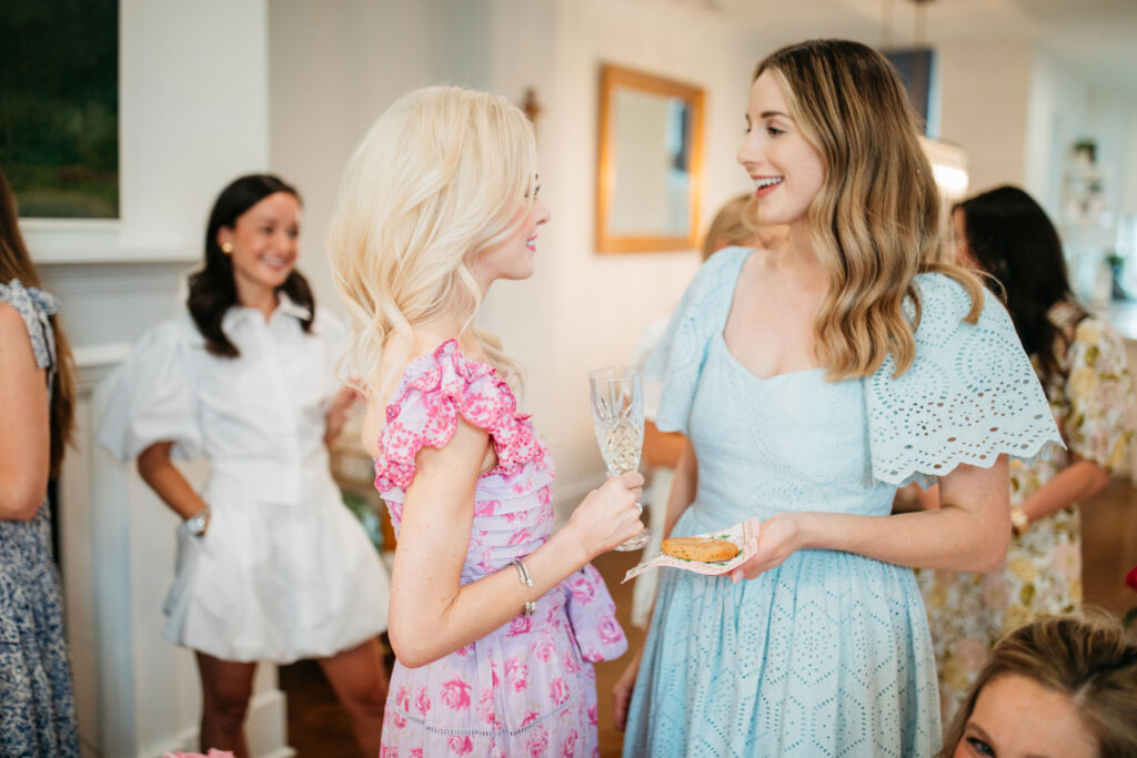 Alison Cheperdak chatting with guests at an elegant social event, demonstrating modern etiquette and gracious hosting with champagne and light refreshments.